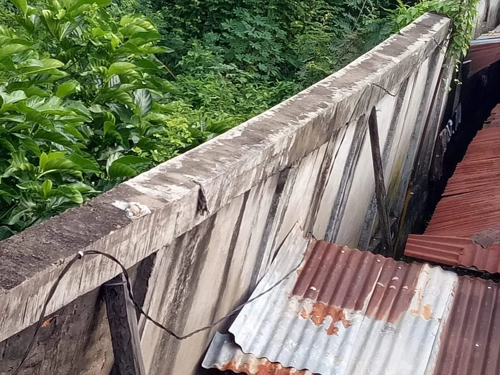 Lihak kondisi kemiringan tembok beton yang hampir roboh menghantam rumah warga. 